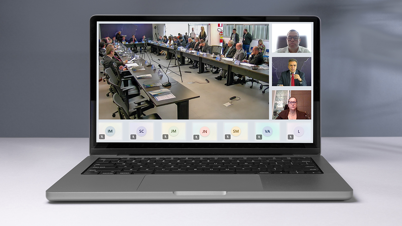 Banner horizontal com foto de um notebook. Na tela, print da reunião realizada. À esquerda, bancada de autoridades. À direita, entre outros, o conselheiro Adircélio de Moraes Ferreira Júnior e o conselheiro Edilson Silva, participando de forma remota.
