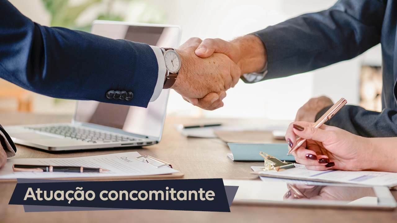Imagem mostra um aperto de mão realizado sobre uma mesa. Na parte inferior, à esquerda, há a expressão Atuação Concomitante