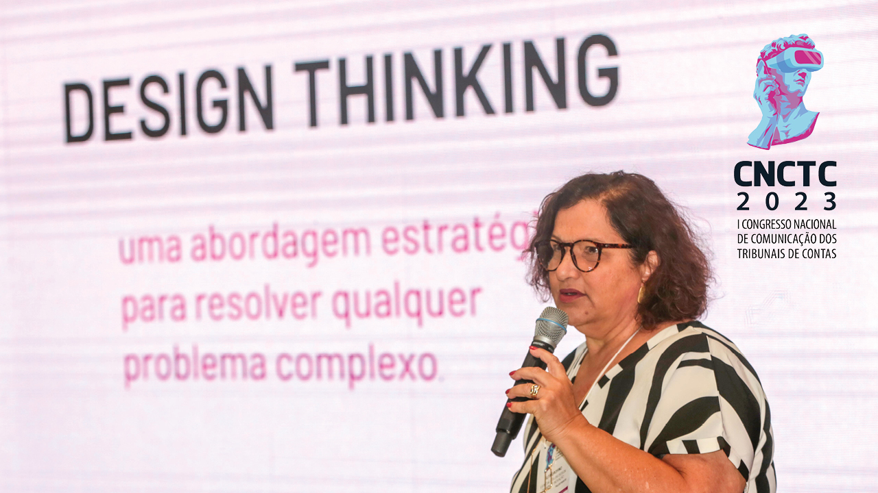 Banner com a foto da palestrante Guta Orofino, em primeiro plano e no lado direito. Ao fundo, painel de led com projeção do texto "Design Thinking - uma abordagem estratégica para resolver qualquer problema complexo". No canto superior direito, o logotipo do evento.