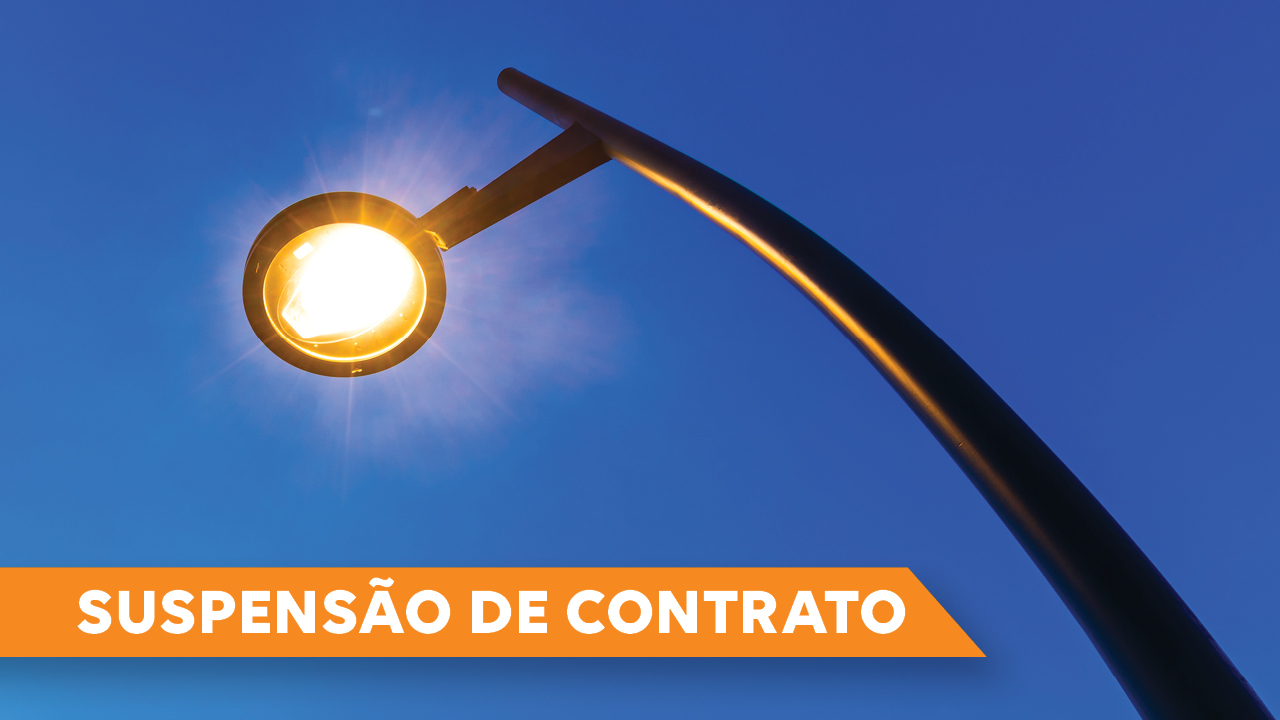 Foto, vista de baixo para cima, de um poste de luz. O fundo é azul-escuro, do céu. No canto inferior esquerdo, há o título “Suspensão de Contrato” sobre retângulo laranja.  