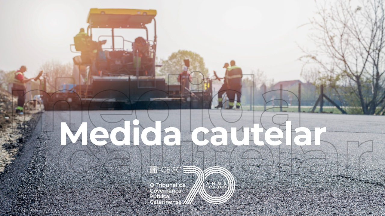 Banner horizontal com foto de uma obra de pavimentação. Em primeiro plano, superfície recém-asfaltada de uma via, enquanto ao fundo aparecem máquinas de construção e trabalhadores atuando no local. Sobre a imagem, em letras brancas, está o texto “Medida cautelar”, acompanhado da marca institucional do TCE/SC. 