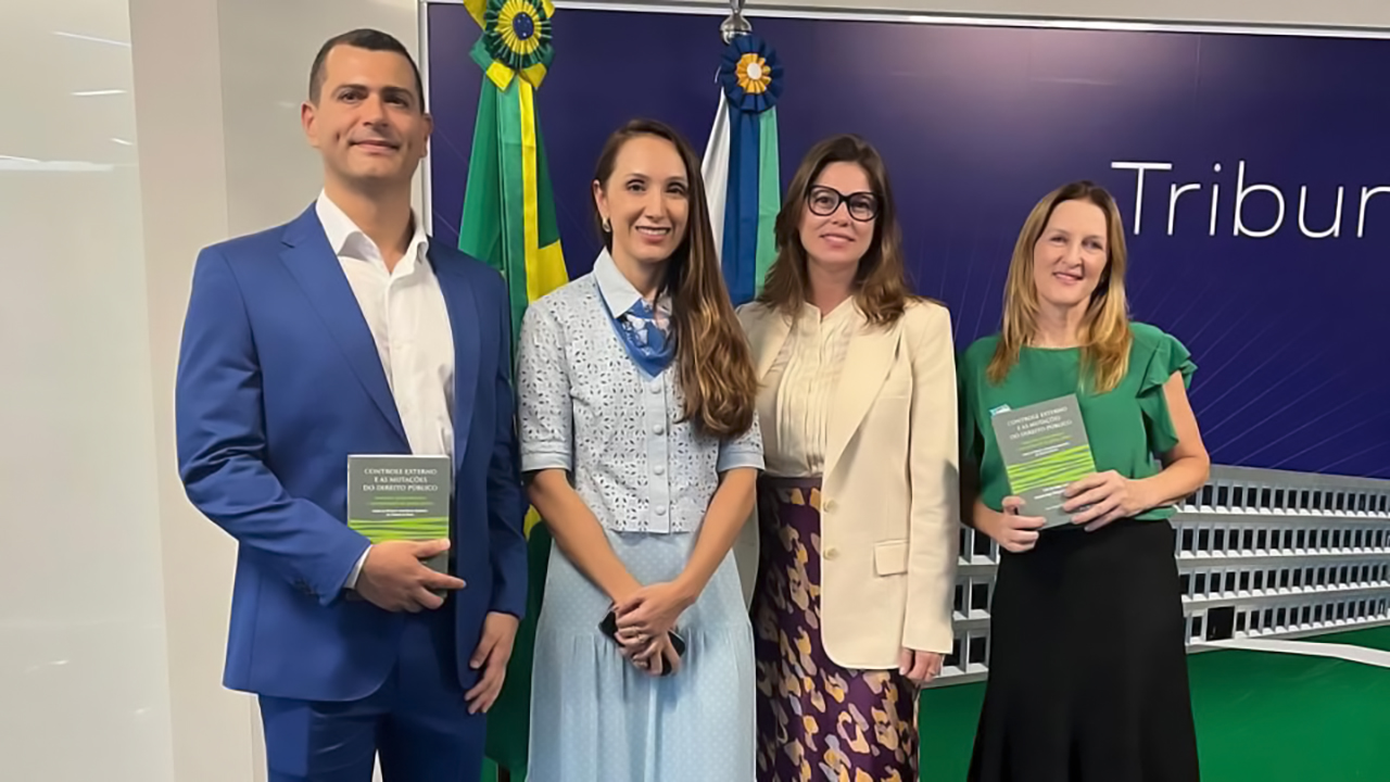Banner horizontal com foto de quatro pessoas em pé, uma ao lado da outra. São elas: a conselheira substituta Sabrina Nunes Iocken e os servidores Sonia de Oliveira (de blusa verde) e Rafael Galvão, ao lado de Milene Cunha (de azul). Ambos sorriem.