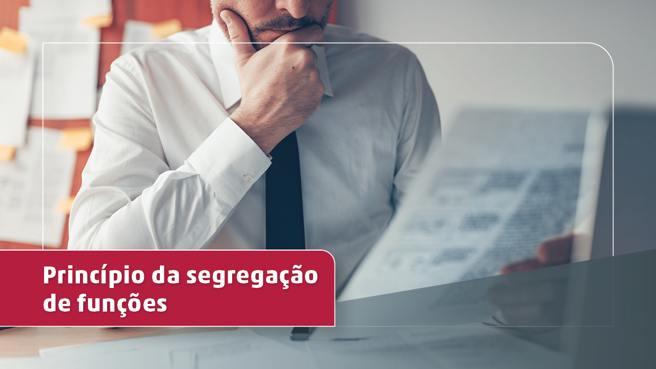 Imagem de um homem num escritório, sentado a frente de uma mesa com computador, de camisa branca e gravata escura, observando uma folha de papel. No canto inferior esquerdo uma tarja em vermelha com o título "Princípio da segregação de funções" em letras brancas., 