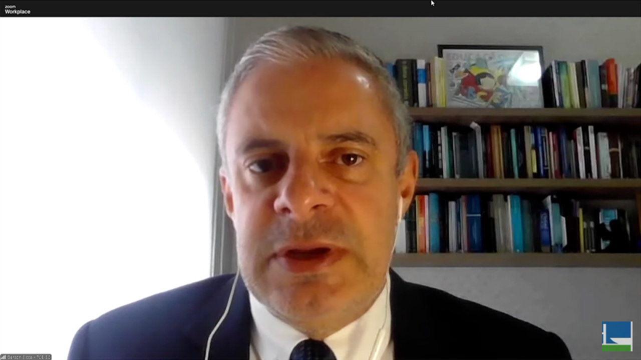 Foto do conselheiro substituto Gerson Sicca durante audiência pública on-line. Sua imagem, cortada do tronco para cima, ocupa a tela inteira. Ele é um homem branco, de cabelos grisalhos. Veste terno e gravata e usa fones de ouvido. 