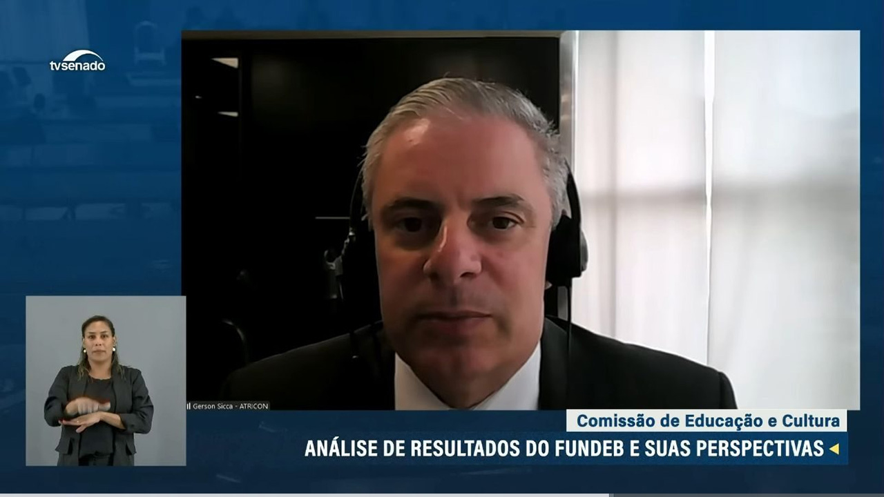 Foto do conselheiro substituto do TCE/SC Gerson dos Santos Sicca. Ele participa – por vídeo chamada- da audiência pública. No canto inferior esquerdo há uma intérprete de libras. No canto superior esquerdo, em letras brancas a logomarca da TC Senado. No canto inferior direito, está escrito, em duas linhas: Comissão de Educação e Cultura - Análise de resultados do Fundeb e suas perspectivas. 