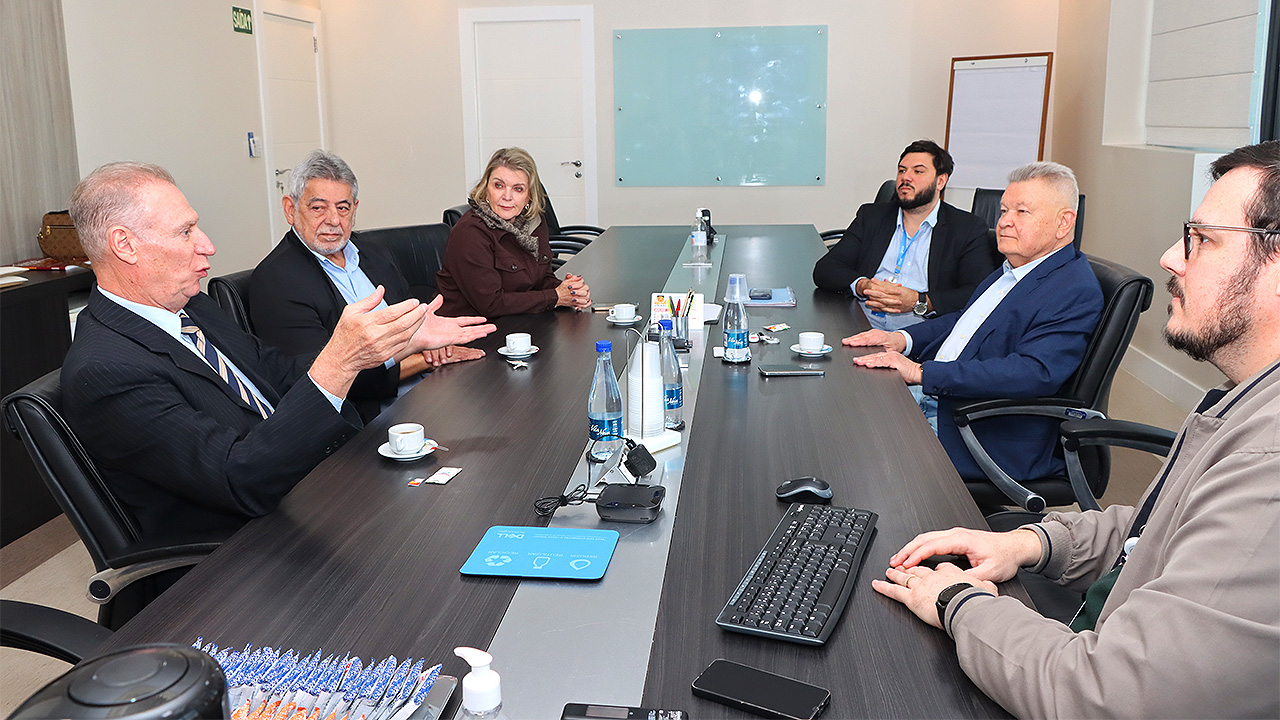 Foto dos participantes da reunião sentados diante de uma mesa enquanto conversam. Há seis pessoas. Entre os presentes, o presidente do TCE/SC, conselheiro Herneus De Nadal e o presidente do Conselho Deliberativo do hospital, Udo Dohler.
