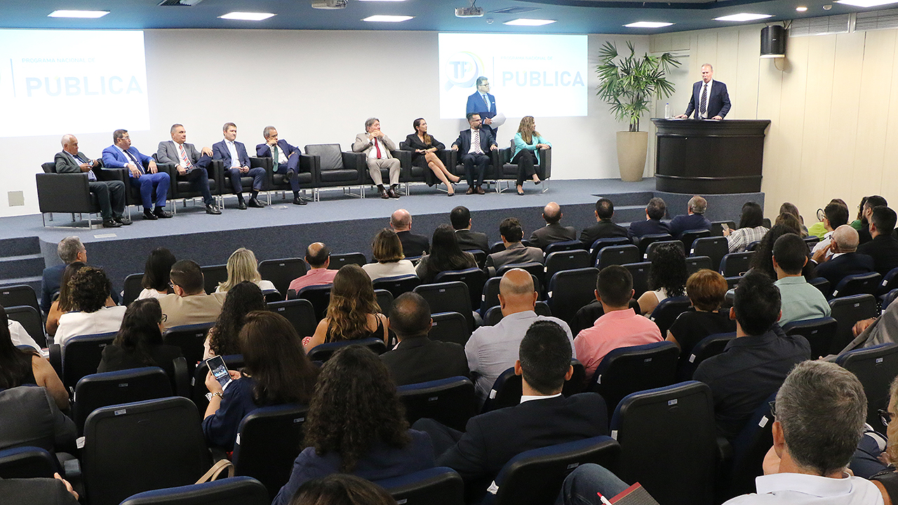 Foto da abertura do treinamento. Ao fundo as autoridade (o presidente do TCE/SC está em pé, no lado direito). à frente, o público participante.