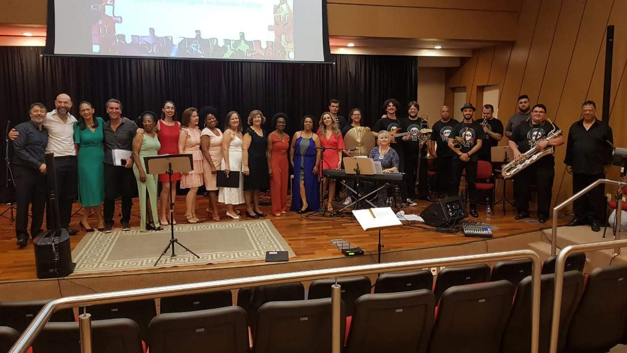 Vinte e dois integrantes do coral, entre homens e mulheres, a soprano Cláudia Todorov, ao teclado, e o barítono Giovane Pacheco, durante apresentação no auditório do TCE/SC. 