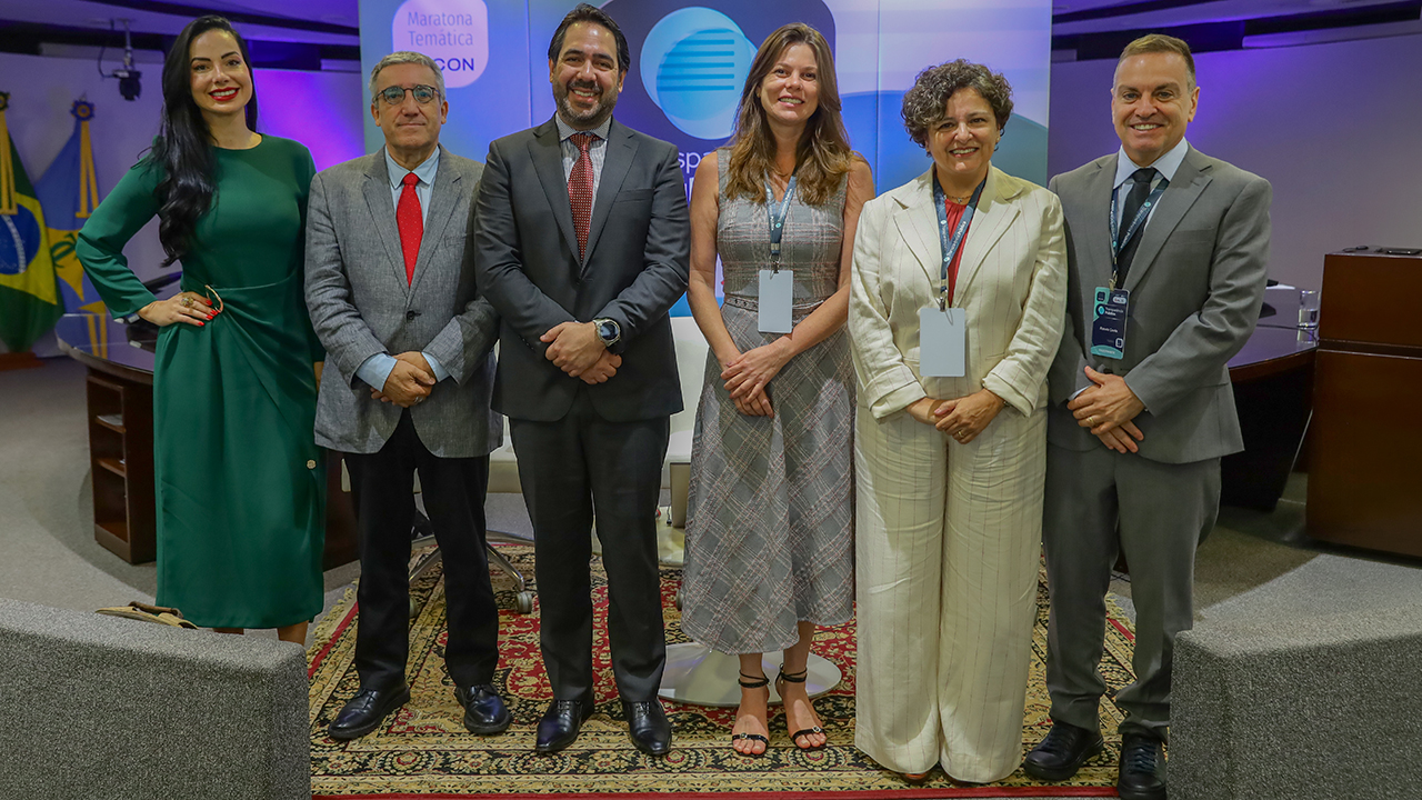 Banner horizontal com foto da conselheira substituta Sabrina Iocken e dos auditores Joseane Aparecida Corrêa e Renato Costa, do TCE/SC, entre outros participantes, durante evento institucional em Brasília, todos posicionados lado a lado em ambiente formal, com uso de crachás e vestimentas sociais, diante de painel temático ao fundo. 