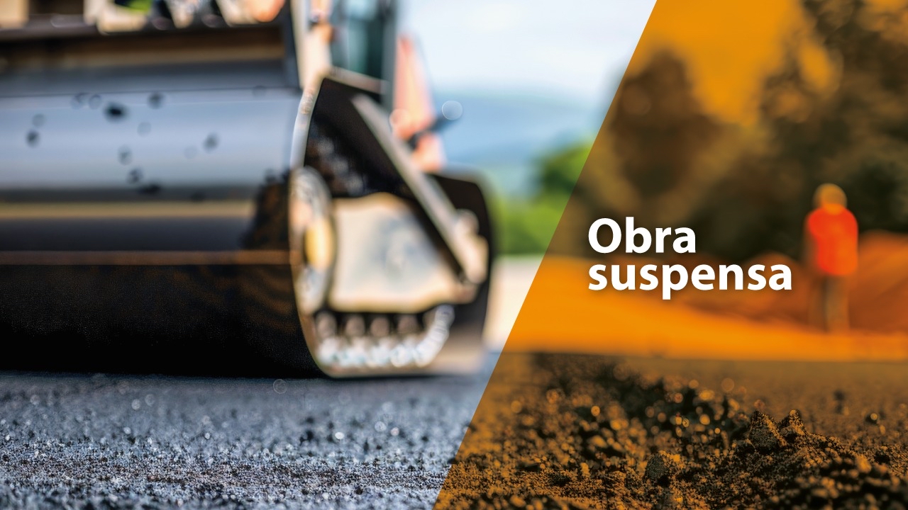 Banner horizontal com foto de uma máquina de pavimentação asfaltando a via. Na lateral direita, sobre tarja vertical laranja, o texto “Obra suspensa”.