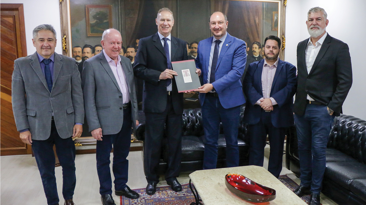 Imagem: Na foto há seis pessoas perfiladas em pé. Ao centro, o presidente do TCE/SC, conselheiro Herneus De Nadal, entrega documento ao presidente da Alesc, Mauro de Nadal