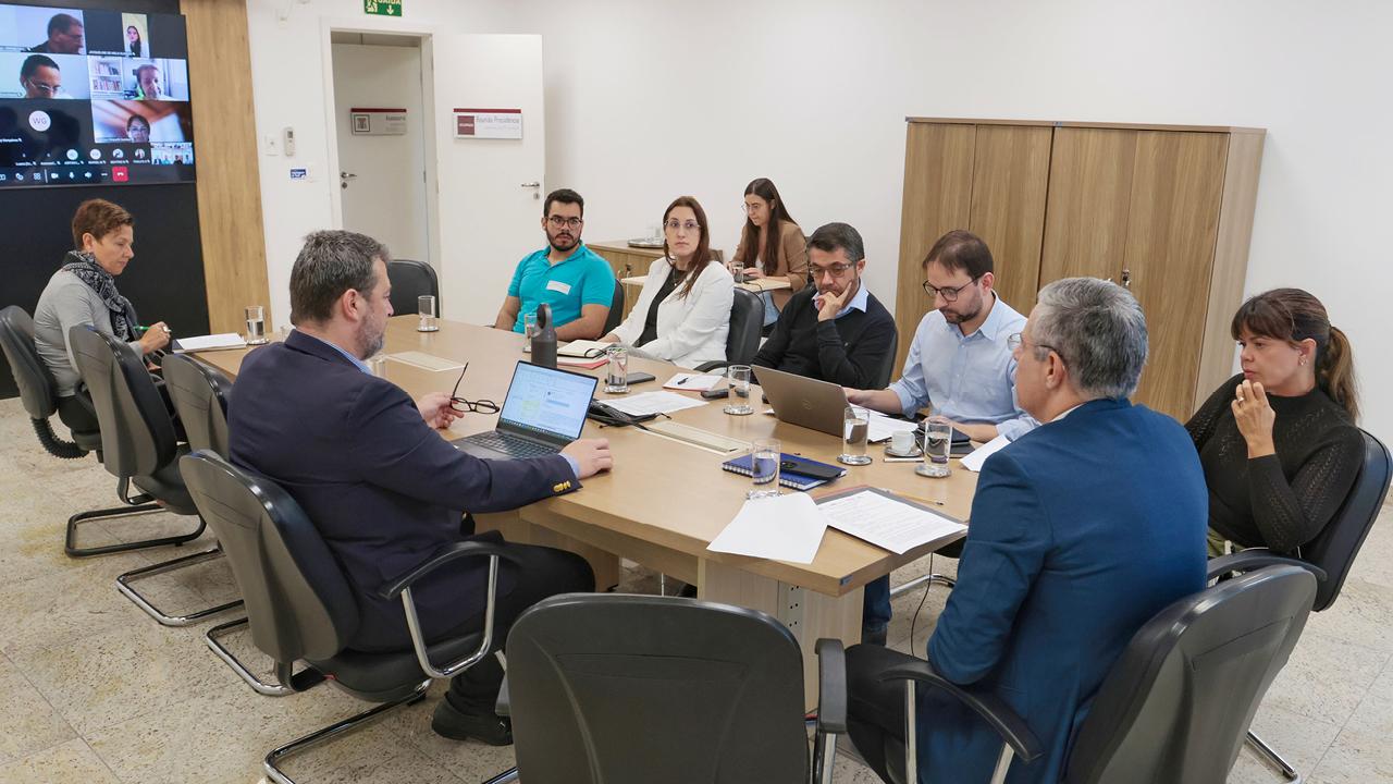 Foto da reunião do Grupo Estratégico de Monitoramento dos Planos de Educação. Há nove pessoas sentadas ao redor da mesa, enquanto conversam. Entre eles, o conselheiro substituto Gerson dos Santos Sicca. 