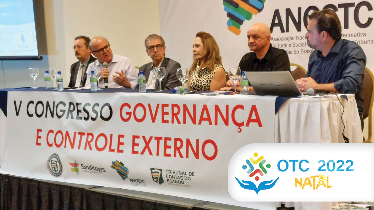 Imagem mostra em primeiro plano uma mesa com faixa onde se lê "Quinto Congresso Governança e Controle Externo". À mesa estão seis pessoas, entre elas o conselheiro do TCE/SC Wilson Wan-Dall, que fala ao microfone