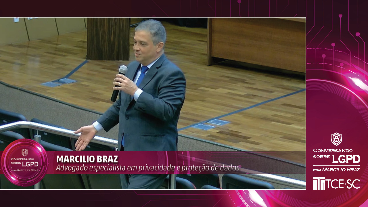 Banner em tons de rosa com marca d'água de circuitos. Ao centro, foto do palestrante Marcílio Braz, que veste um terno cinza e gravata azul-marinho e segura um microfone enquanto fala. No canto inferior direito, há o texto Conversando sobre LGPD com Marcílio Braz. Abaixo, há o logotipo do TCE/SC, ambos em cor branca.