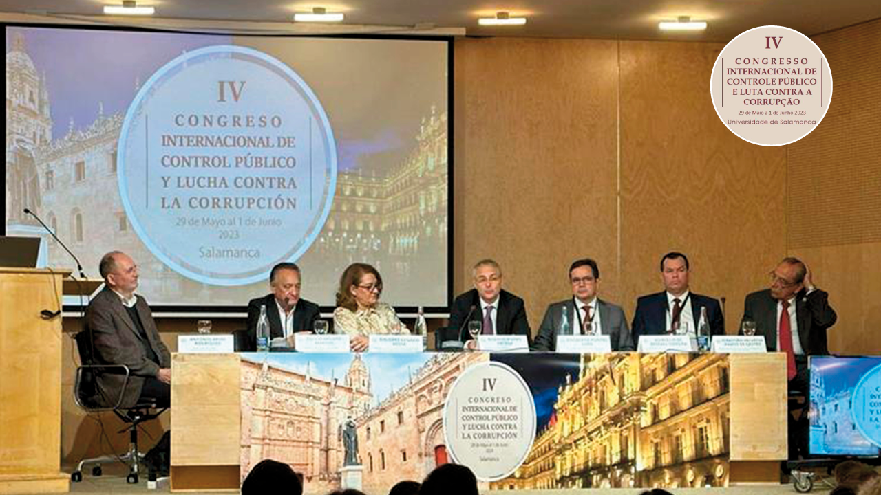 Foto da mesa de autoridades no evento. Ao todo, há cinco homens brancos que vestem terno, entre eles o conselheiro Adircélio, e uma mulher, também de pele branca, que veste uma blusa florida. Ao fundo, há a projeção do logotipo do Congresso, com a inscrição "Congreso Internacional de Control Público y Lucha Contra la Corrupición"..