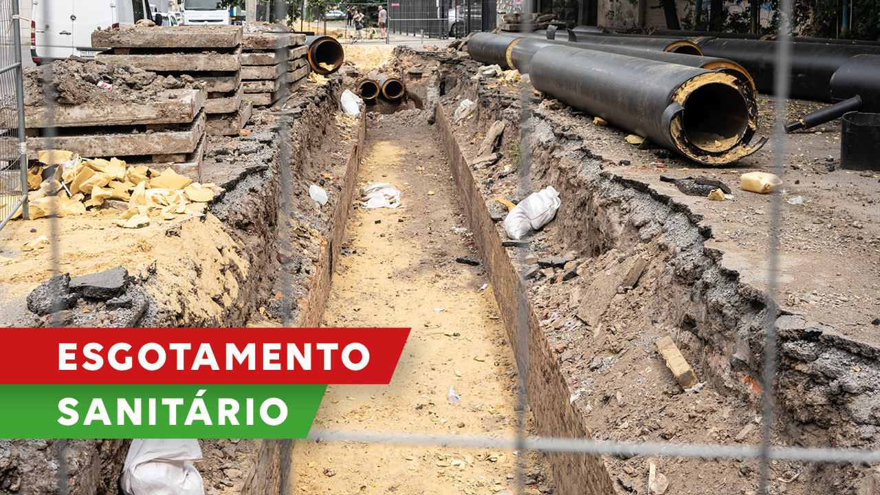 Banner horizontal com foto de uma obra inacabada de estação de tratamento de esgoto. No canto inferior esquerdo, sobre retângulo vermelho há o título "Esgotamento” e abaixo, sobre retângulo verde, a palavra “sanitário”. 