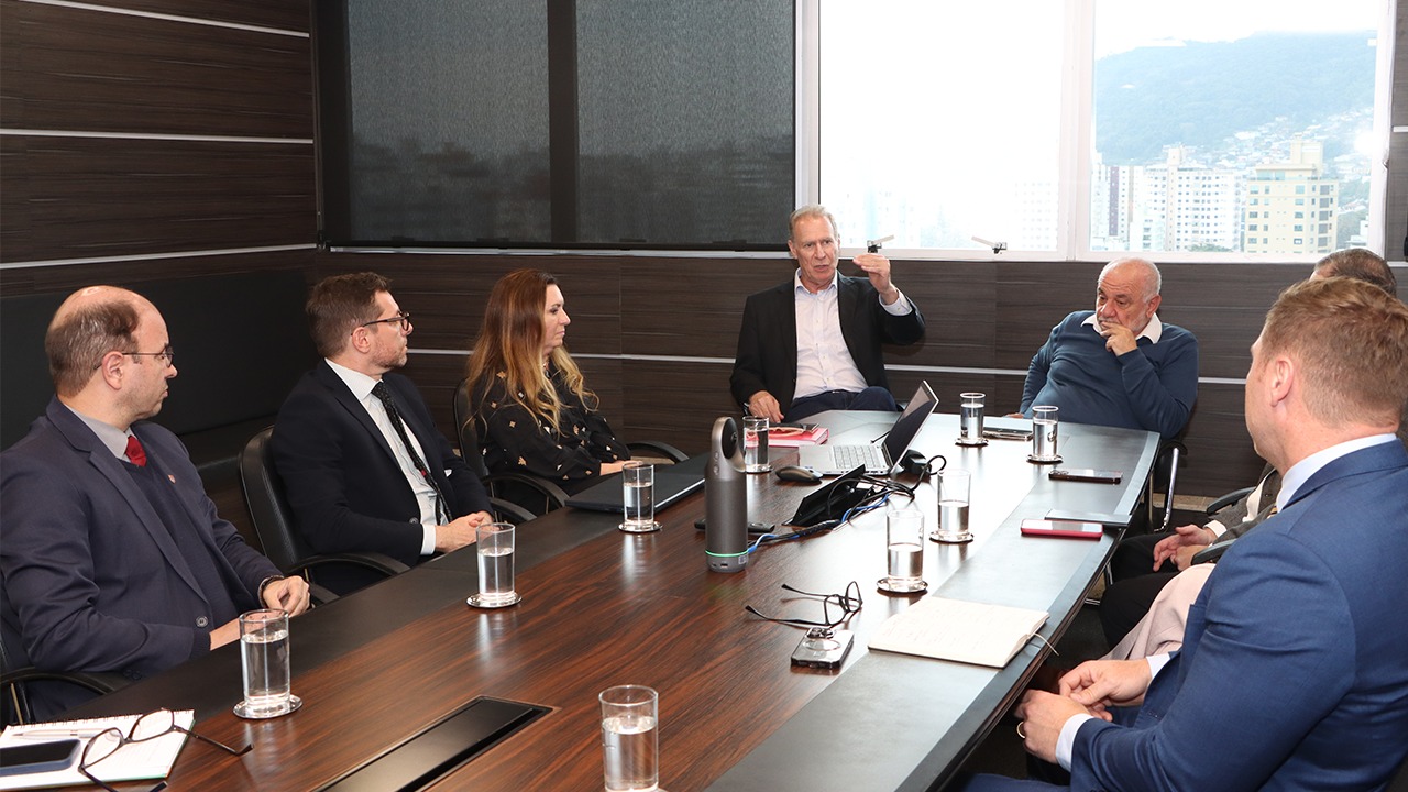 Foto da reunião realizada entre o TCE/SC e o TJSC. Há oito pessoas sentadas ao redor de uma mesa, enquanto conversam. Entre os presentes, o presidente Herneus De Nadal, o conselheiro Luiz Eduardo Cherem e a juíza auxiliar da presidência do TJSC, Maira Salete Meneghetti.