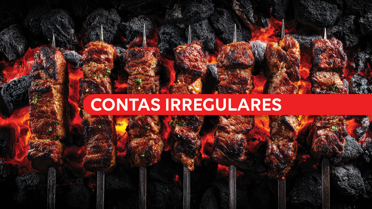 Banner horizontal com foto de vários espetos de carne assando sobre brasas e carvão em brasa, com aspecto dourado. Ao centro da imagem, uma faixa vermelha atravessa horizontalmente os espetos com o texto “Contas irregulares” em letras brancas e destacadas. 