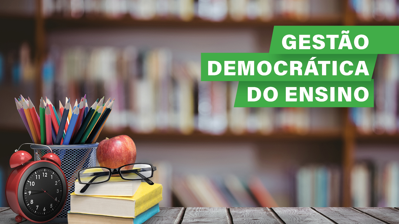 Banner horizontal com fundo desfocado com diversos livros em prateleiras. A frente e na parte superior, o texto “Gestão democrática do ensino”, em fonte branca e em retângulos verdes. E, na parte inferior, sobre um balcão de madeira, um relógio vermelho, três livros (sendo dois com capas amarelas e um com capa azul), óculos, maçã e diversos lápis de cor. 