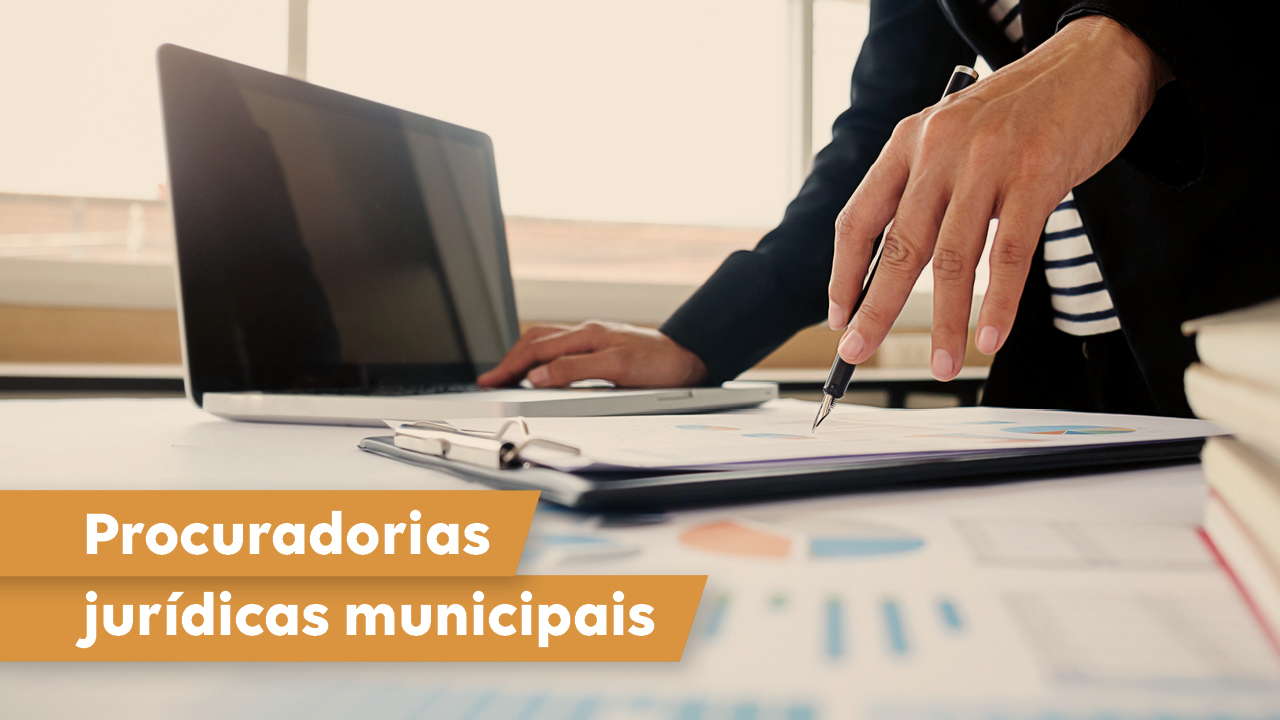 Banner horizontal com foto de uma pessoa mexendo em um laptop e segurando uma caneta sobre papéis, dispostos sobre uma mesa. A foto está cortada, de modo que não é possível ver o seu rosto. No canto inferior esquerdo, sobre tarjas amarelas, o texto “Procuradorias jurídicas municipais”. 