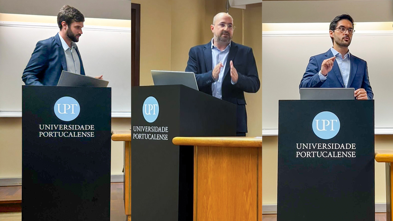 Banner horizontal com a foto dos auditores fiscais de Controle Externo Rafael Scherb, Renato Bossle Miguel e Juliano Frassetto, na Universidade Portucalense, discursando no púlpito.