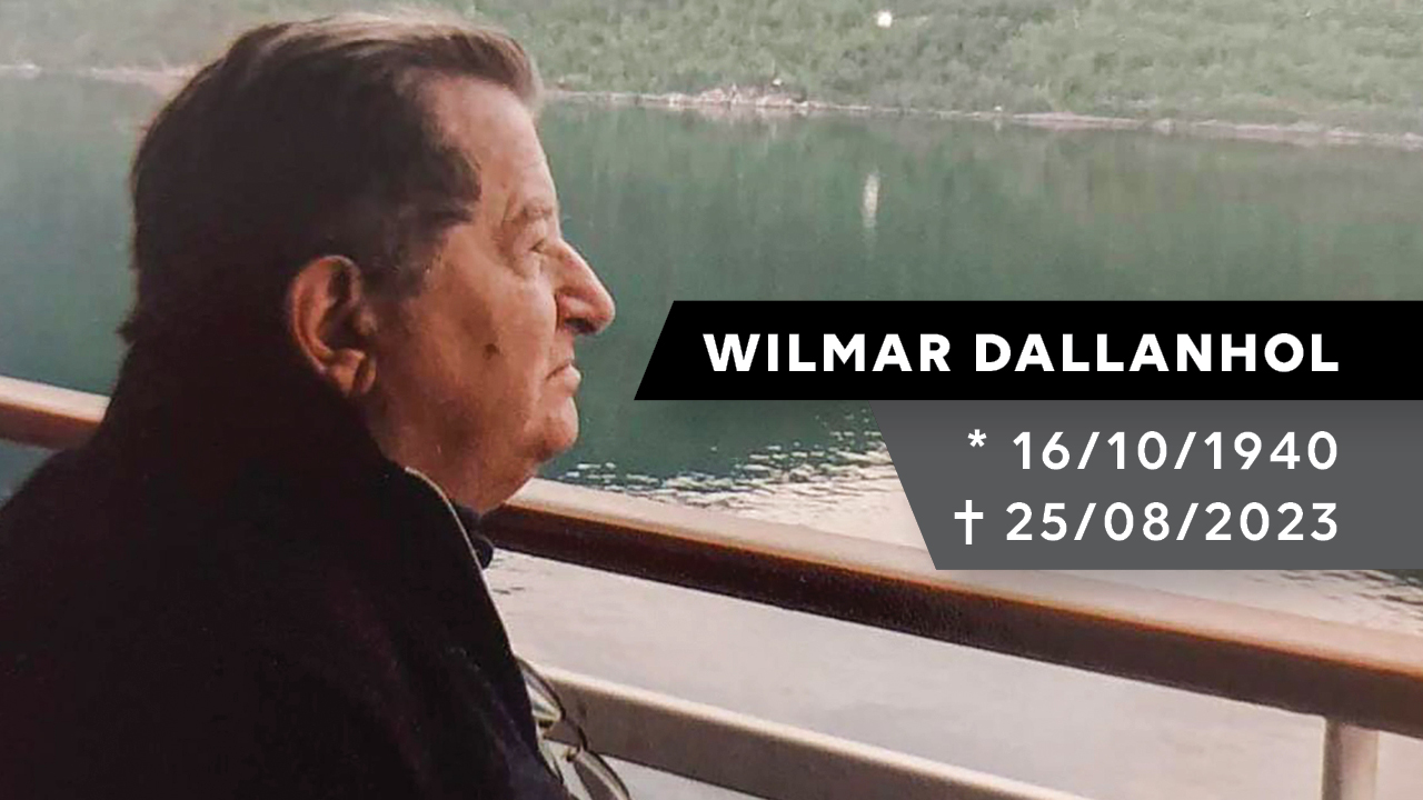 Fotografia do e-presidente Wilmar Dallanhol, de perfil. ele é um homem branco eusa uma blusa preta. Está de perfil. Ao fundo, um rio. No lado direito está escrito "Wilmar Dallanhol. 16/10/1940. 25/8/2023"