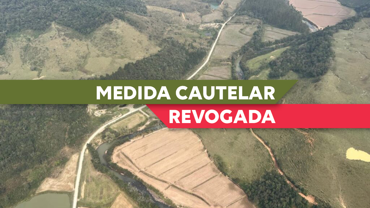 Banner horizontal, com foto aérea de região similar onde será construída a barragem do Rio Taió, em Mirim Doce. No centro, sobre uma tarja verde e com letras brancas a expressão Medida Cautelar. Abaixo, sobre uma tarja vermelha, também em letras brancas, a palavra Revogada.
