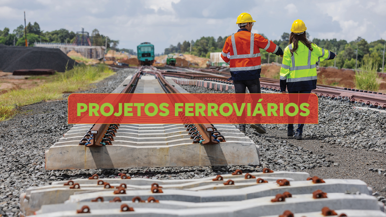 Banner horizontal com foto de uma ferrovia em construção. Em primeiro plano, aparecem trilhos recém-instalados sobre estruturas de concreto e brita. Ao centro da imagem, dois profissionais com capacetes e coletes de segurança caminham ao longo da via férrea, observando e apontando para a área da obra. Uma faixa vermelha semitransparente destaca o texto “Projetos ferroviários” ao centro. 