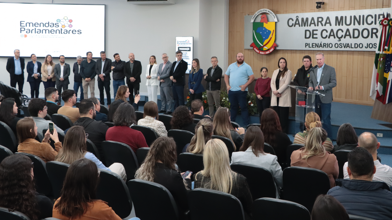 Banner horizontal com foto de comitiva do TCE/SC posicionada no palco do auditório. No púlpito, discursa o presidente Herneus De Nadal. À frente, o público participante.