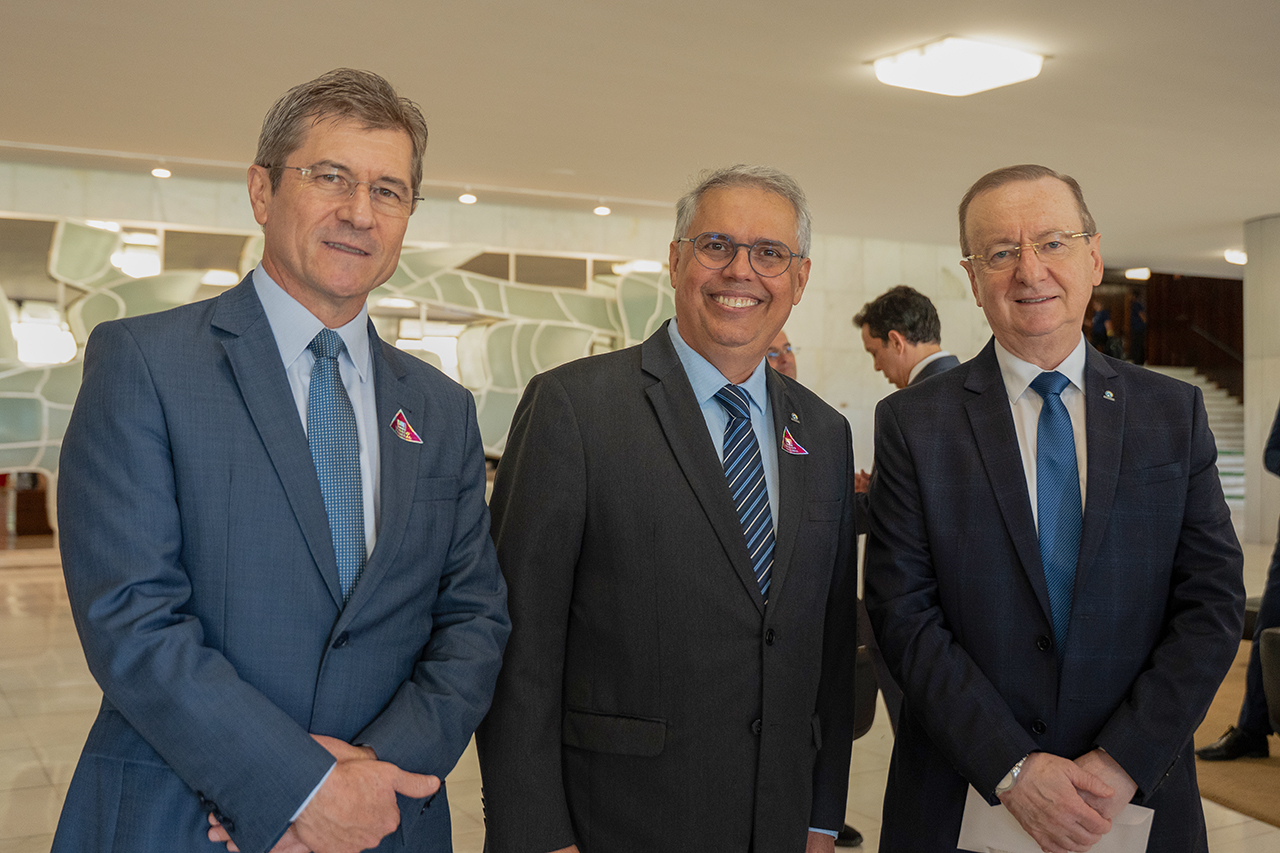 Foto horizontal do vice-presidente do TCE/SC, conselheiro José Nei Ascari, ao lado dos conselheiros Severiano Costandrade de Aguiar e Cezar Miola. Os três vestem terno e gravata e estão em pé, em ambiente interno institucional. 