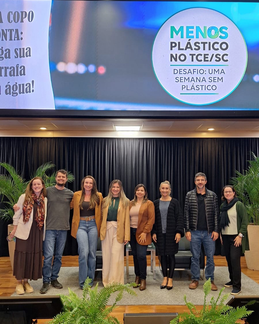 Foto de oito pessoas que compõem a Comissão ASG no palco do auditório do TCE/SC, durante o evento. Elas estão uma ao lado da outra. Entre os presentes, a coordenadora, Marina de Miranda.