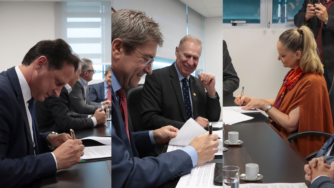 Imagem com mosaico de três fotos que mostram as autoridades assinando o acordo. Há várias pessoas na reunião, em torno de uma mesa. 