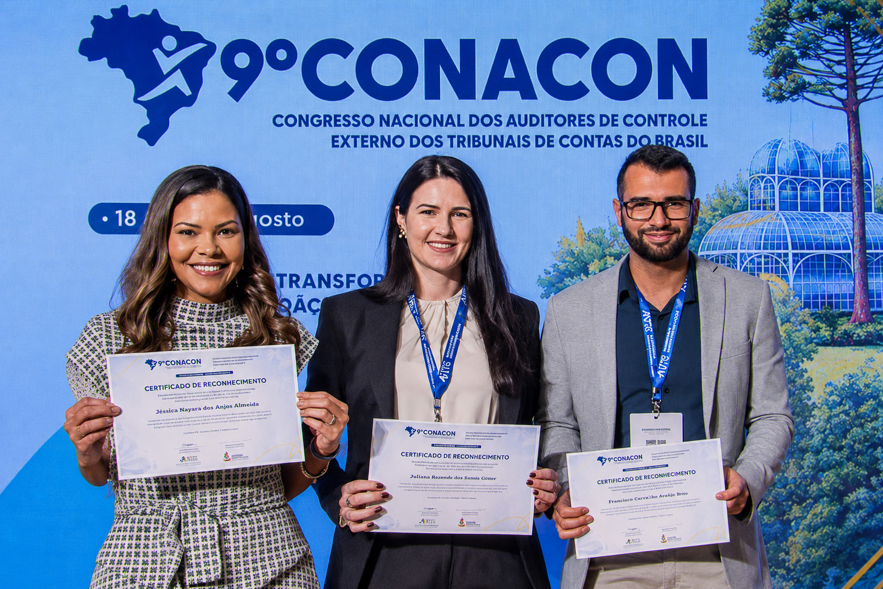 Foto horizontal de três pessoas com o certificado da homenagem recebida. Ao centro,  auditora fiscal de controle externo do TCE/SC Juliana Medeiros das Neves Moser. 