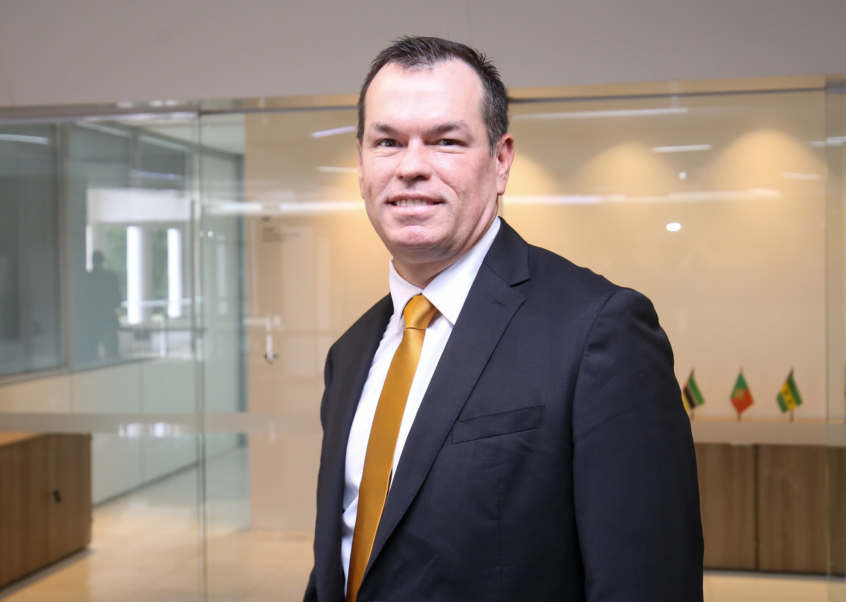 Banner horizontal com foto do conselheiro Adircélio de Moraes Ferreira Júnior. Ele é um homem branco, de cabelos castanhos. Veste terno e gravata e sorri. Está em pé, em um ambiente interno. 