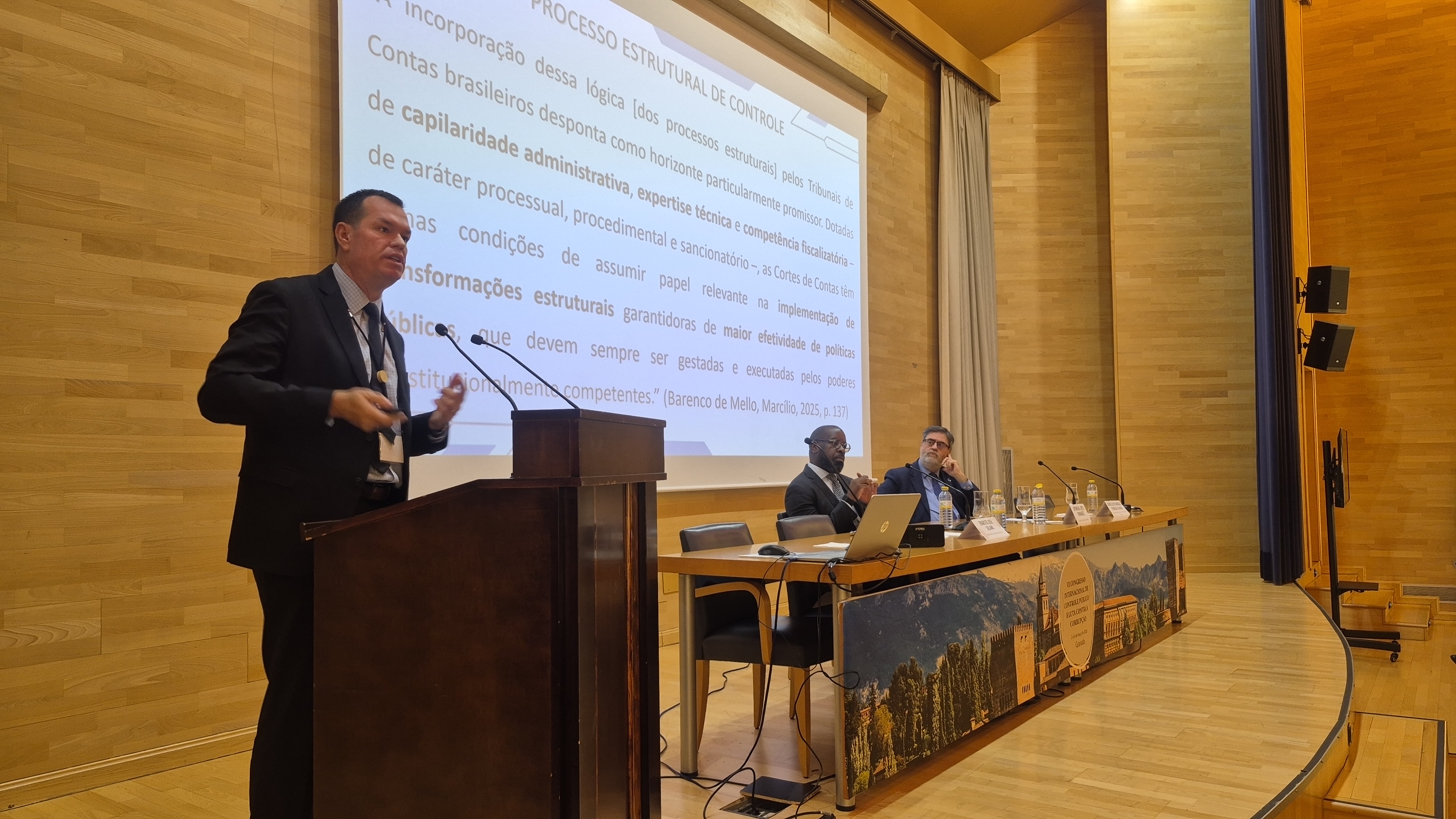 Foto horizontal em auditório durante programação do congresso, mostrando o conselheiro Adircélio de Moraes Ferreira Júnior, ao púlpito, enquanto autoridades compõem a mesa no palco.