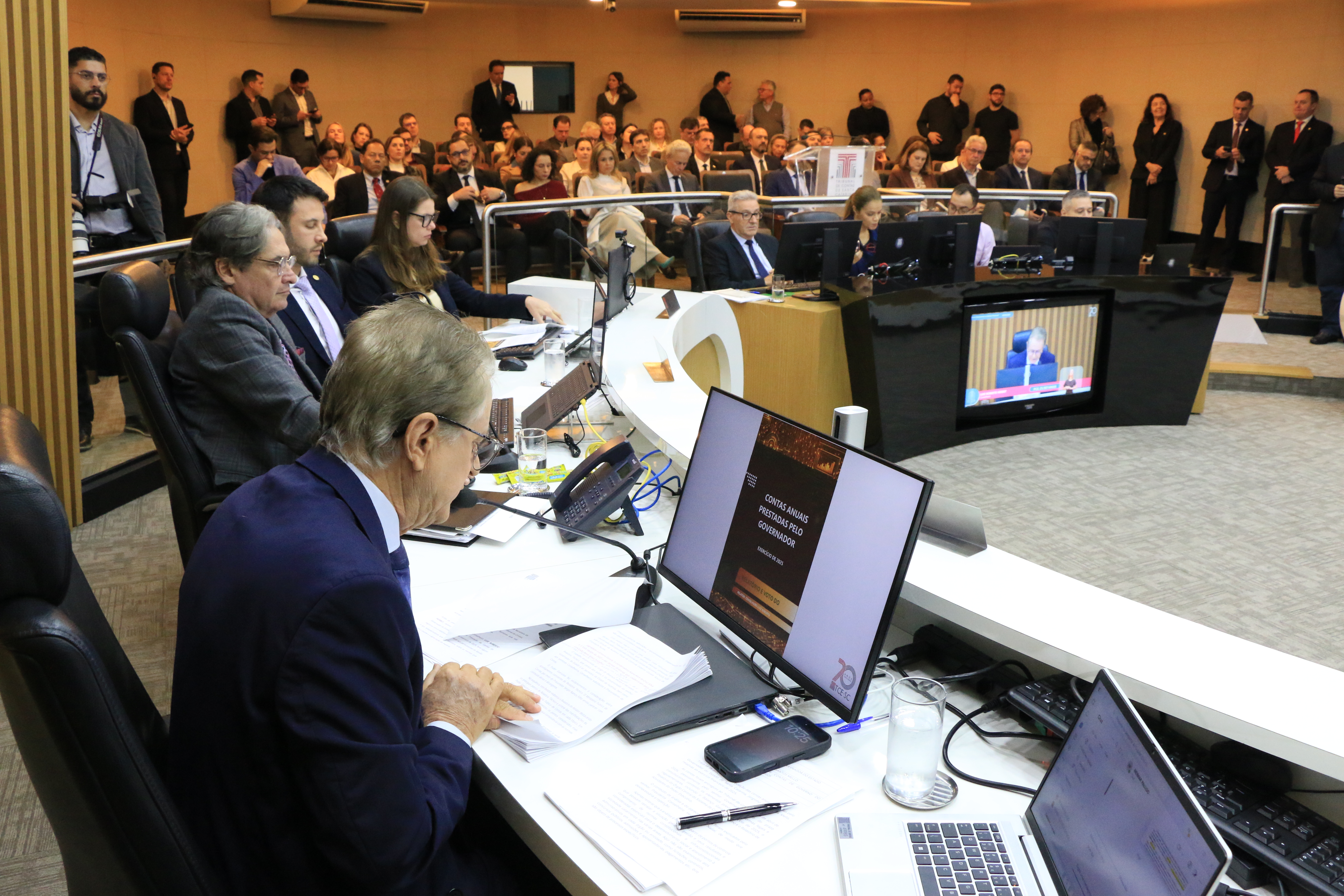 Foto horizontal da sessão do Pleno. Em primeiro plano, o relator do processo, conselheiro Luiz Roberto Herbst, ao lado de integrantes do Pleno. o fundo, a plateia.
