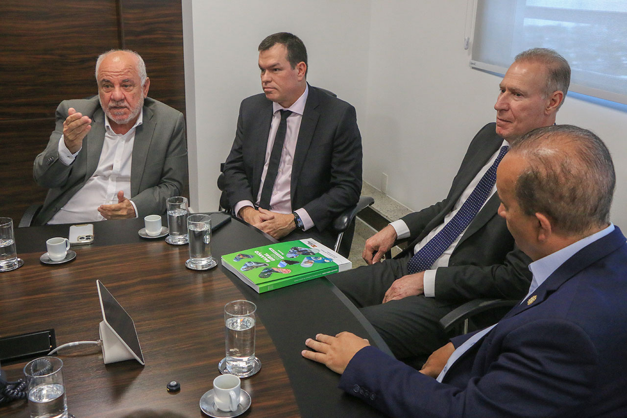 Banner horizontal com foto dos conselheiros Luiz Eduardo Cherem, Adircélio de Moraes Ferreira Júnior e Herneus De Nadal sentados ao lado do governador do estado, Jorginho Mello, enquanto conversam. Eles estão em reunião, diante de uma mesa, sobre a qual está o Balanço Geral do Estado. 