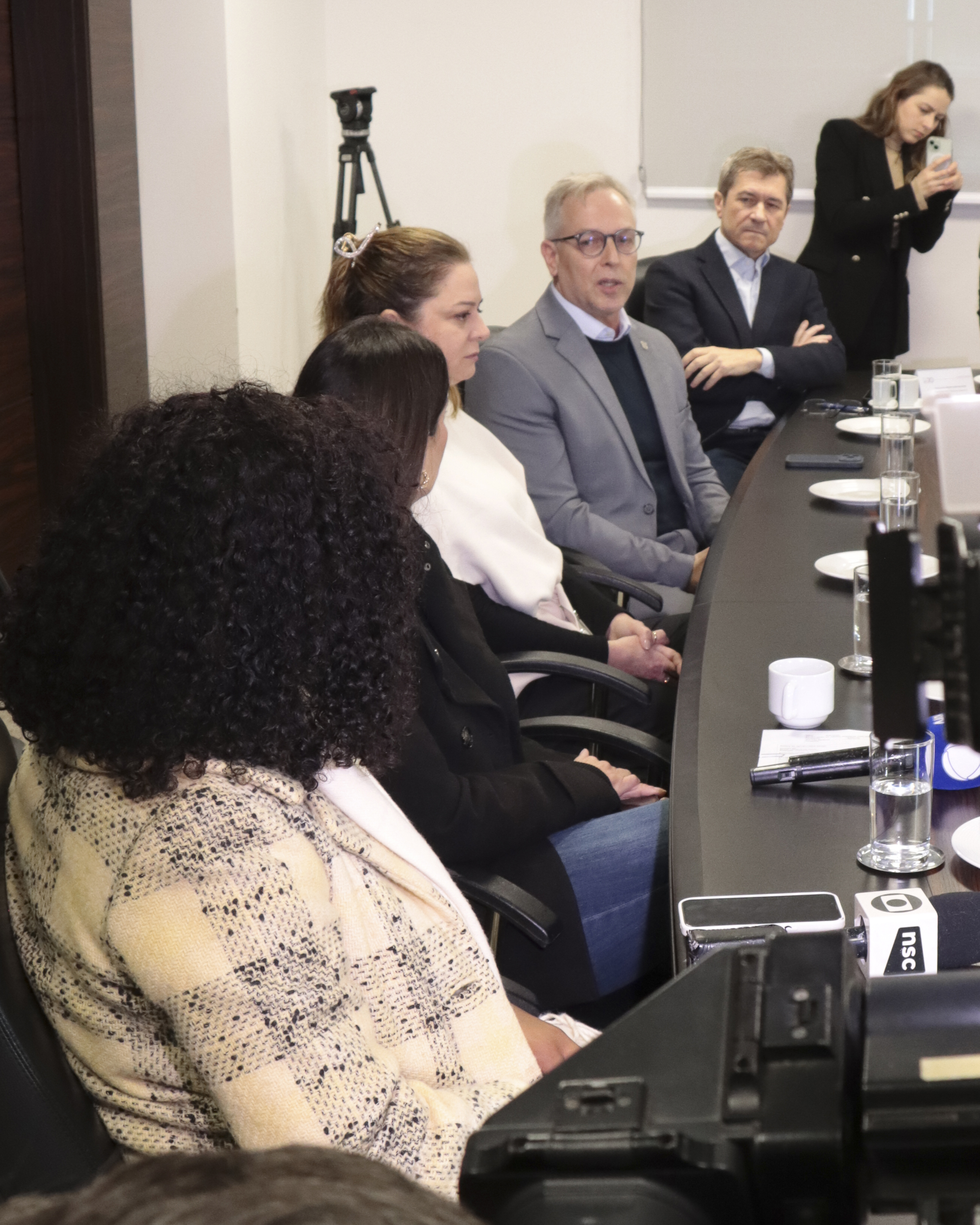 Foto vertical de vários participantes da reunião sentados lado a lado, diante da mesa. Entre os presentes, o vice-presidente, conselheiro José Nei Ascari, o diretor Sidney Tavares Júnior e outros servidores.