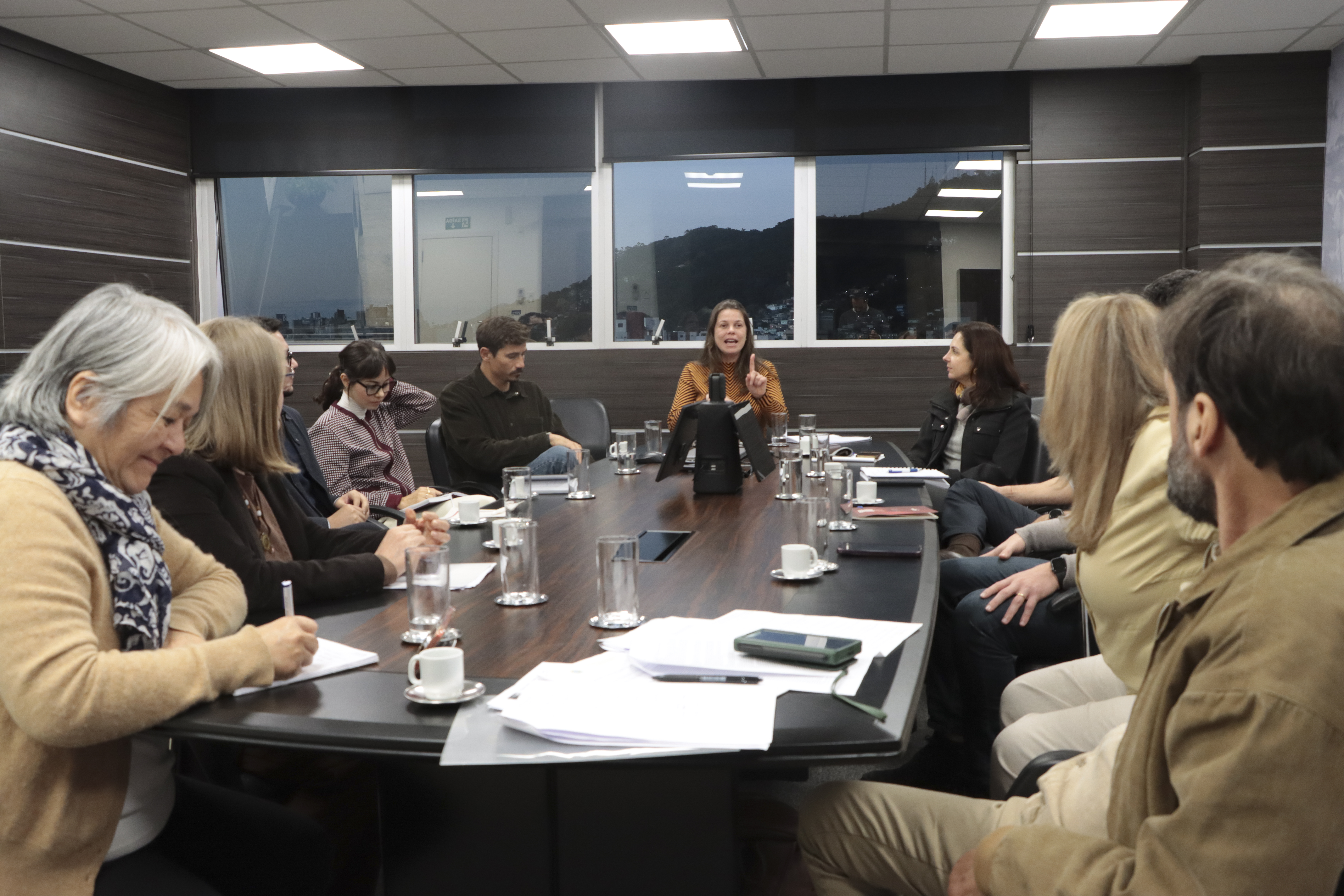 Foto horizontal que mostra os participantes reunidos, sentados diante de uma mesa. Entre os presentes, a conselheira substituta Sabrina Iocken, integrantes do Consea-SC e do TCE/SC. 