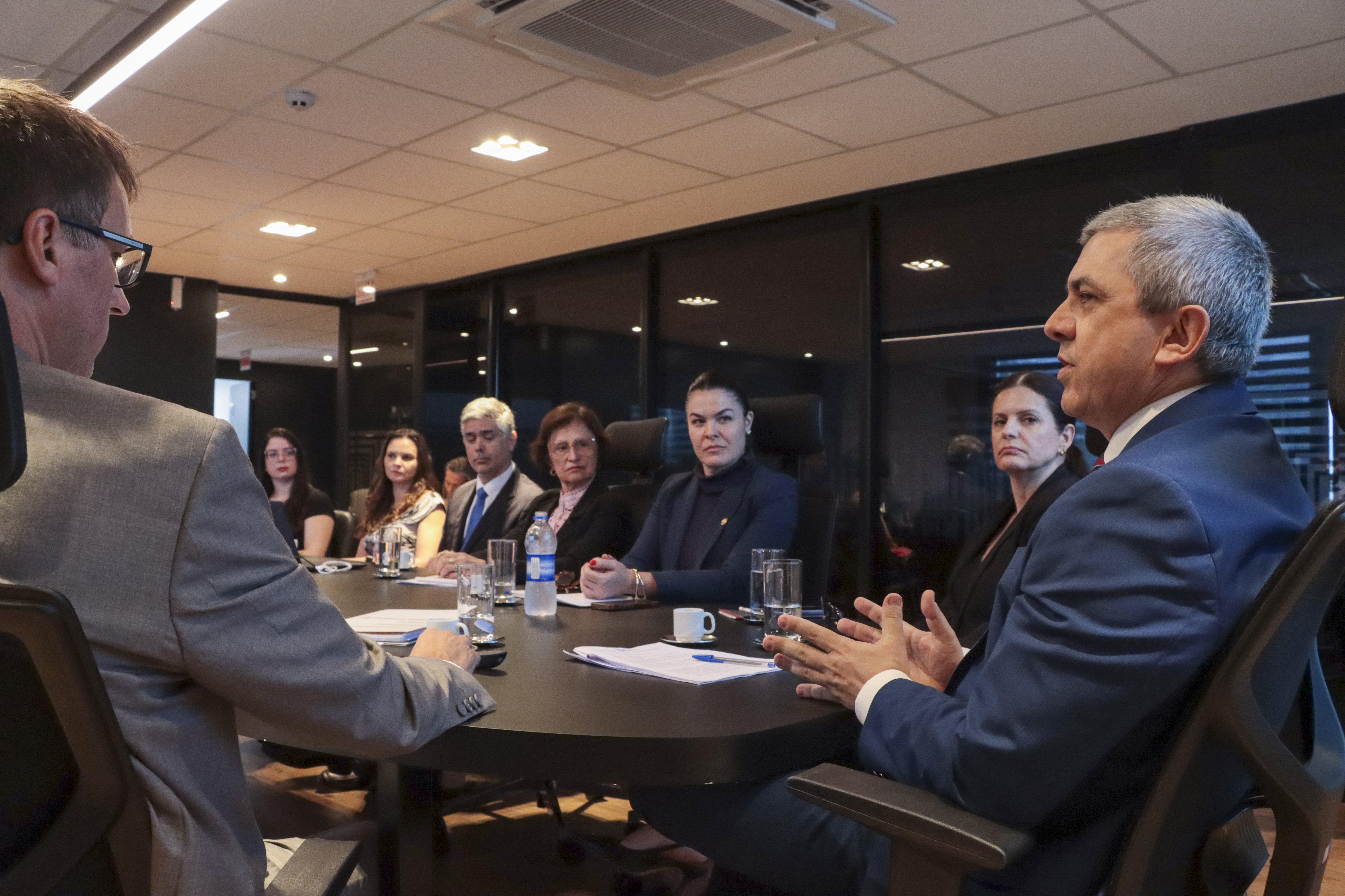 Banner horizontal com foto das autoridades durante reunião da mesa de consensualismo. Entre os presentes, o coordenador da mesa, auditor Márcio Medeiros, a diretora-geral adjunta de Controle Externo do TCE/SC, Monique Portella, e a auditora Cláudia Lemos, do gabinete do conselheiro José Nei Ascari, além de outros integrantes das demais instituições.
