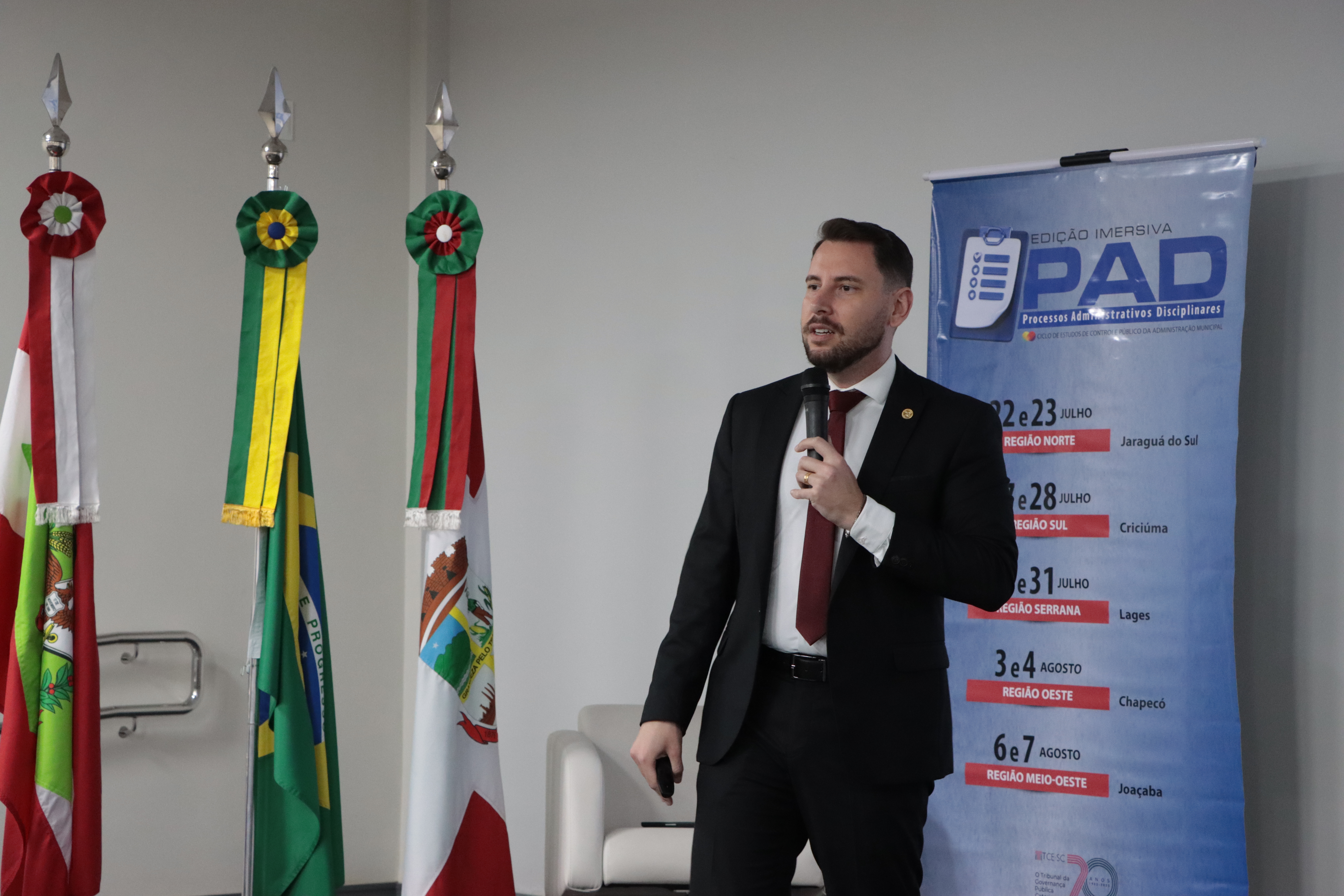 Foto do palestrante Geovane Eziel Cardoso. ele está palestrando, ao fundo o banner do PAD.