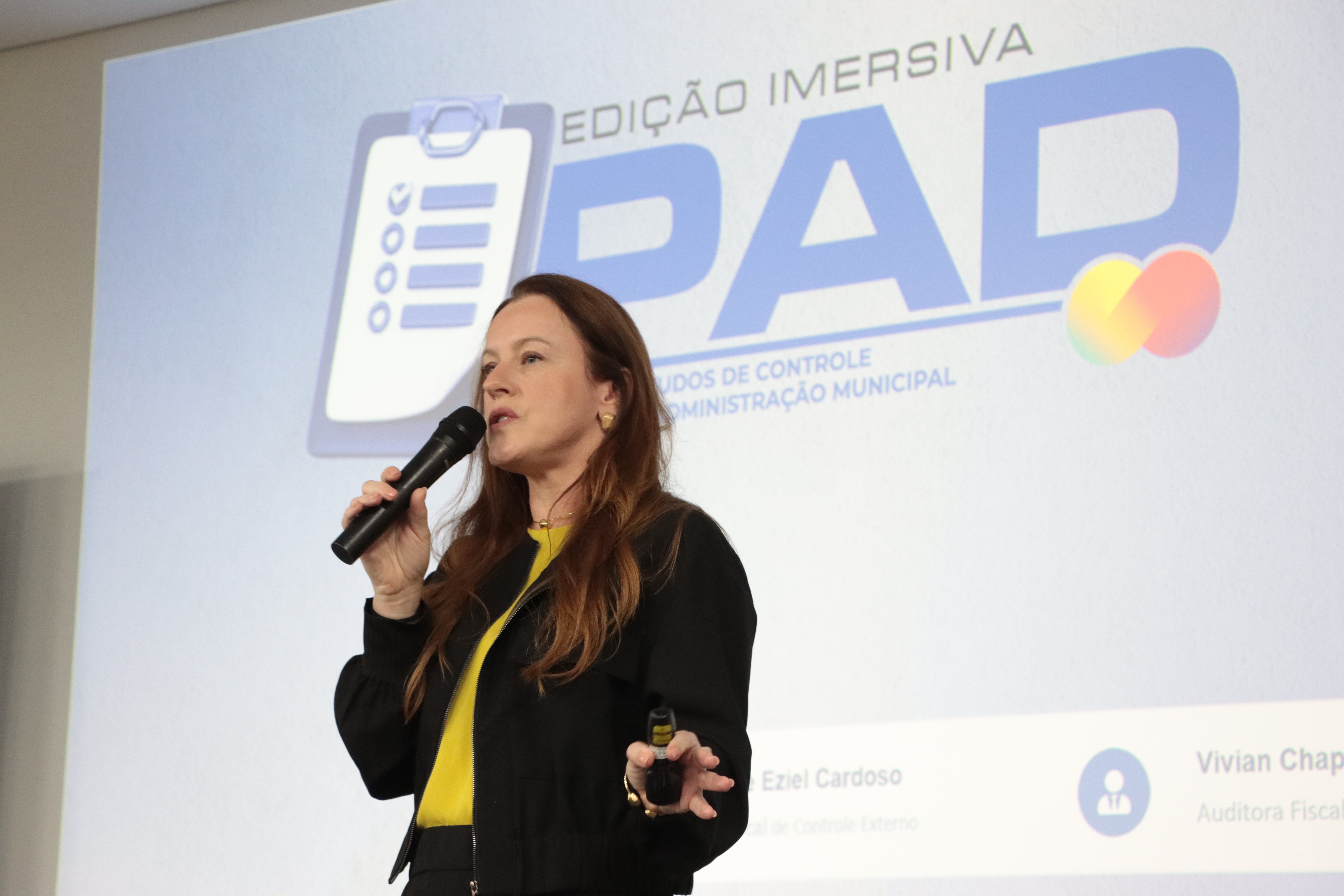foto da palestrante Vivian Chaplin Ganzo Savedra. Ao fundo o banner do PAD.