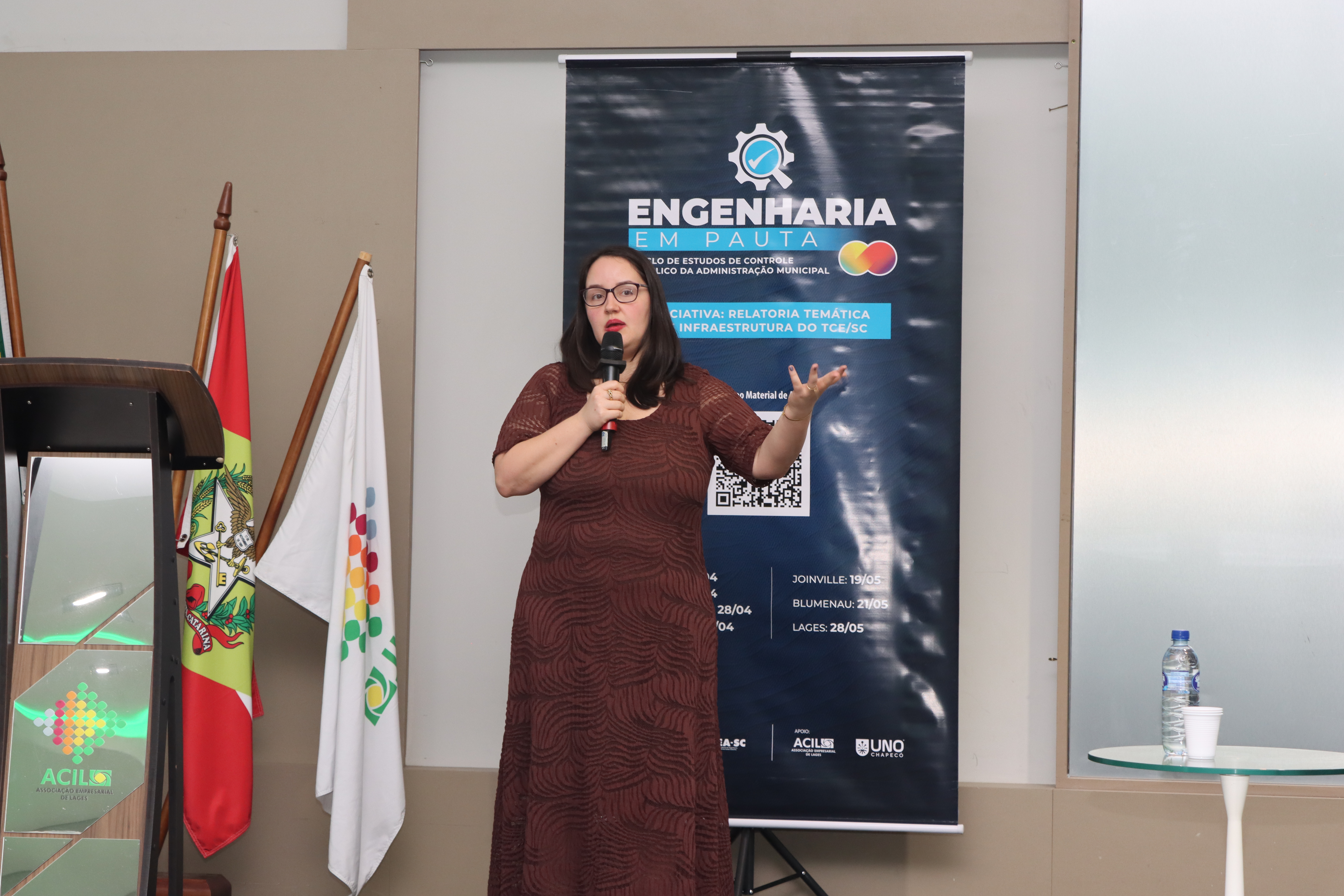 Foto da coordenadora de obras e serviços de engenharia da DLC Renata Ligocki Pedro palestrando.