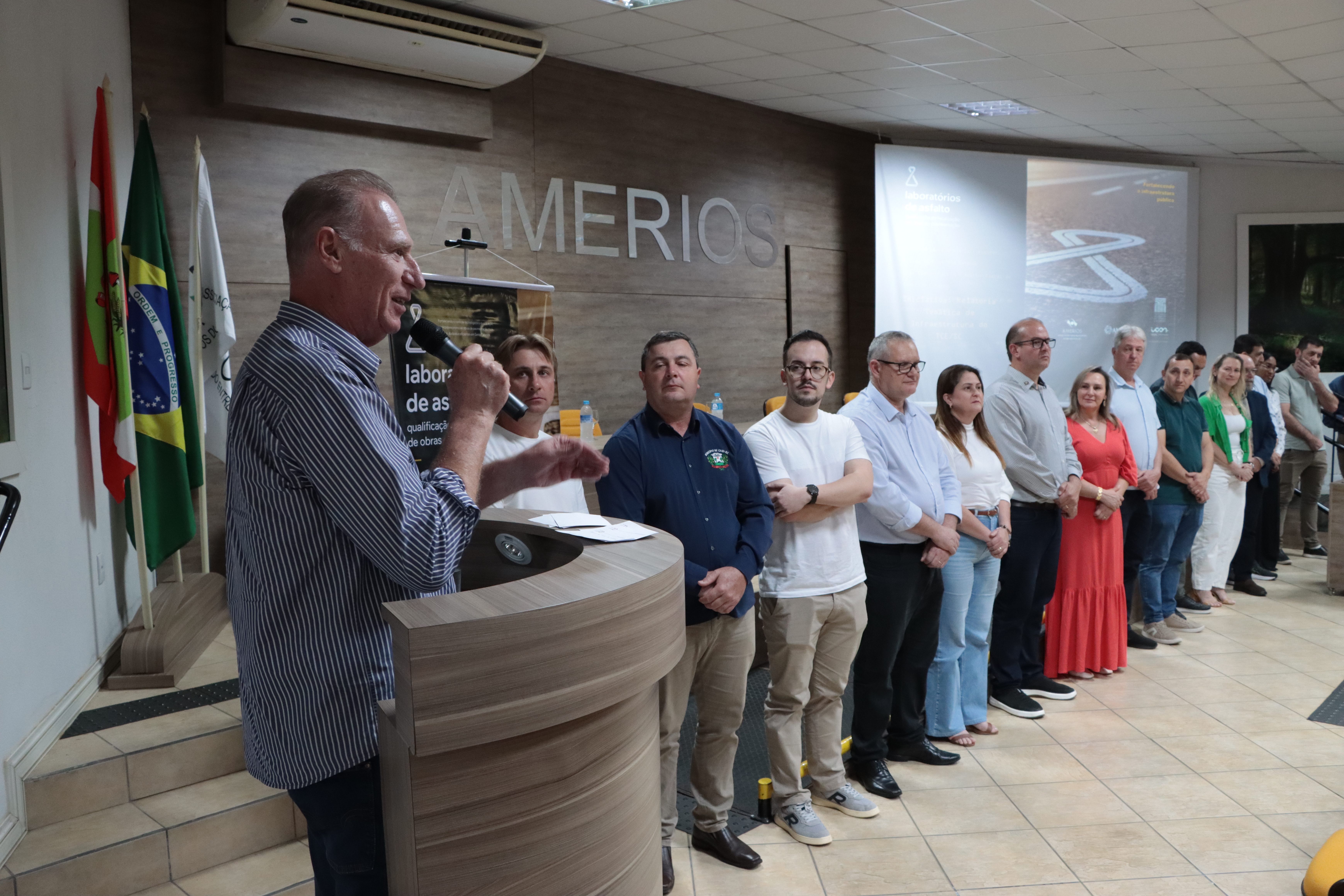 Foto  horizontal. À direita, no púlpito, o presidente do TCE/SC,conselheiro Herneus De Nadal discursa. Ao lado, os diversos prefeitos presentes ao evento.