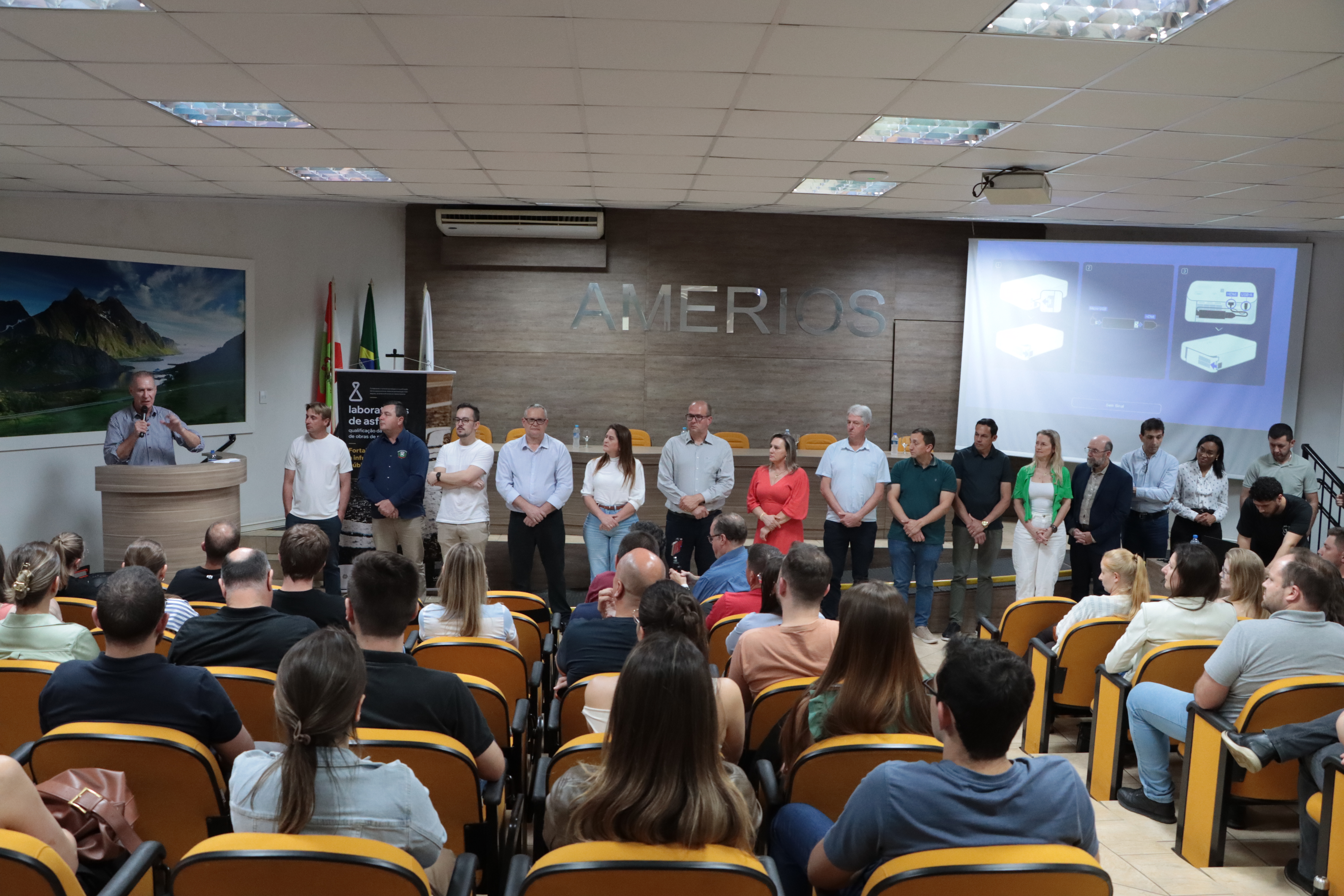 Foto horizontal do auditório praticamente lotado. No palco, à esquerda, o presdiente do TCE/Sc discursa. No centro, as diversas autoridades presentes ao evento.
