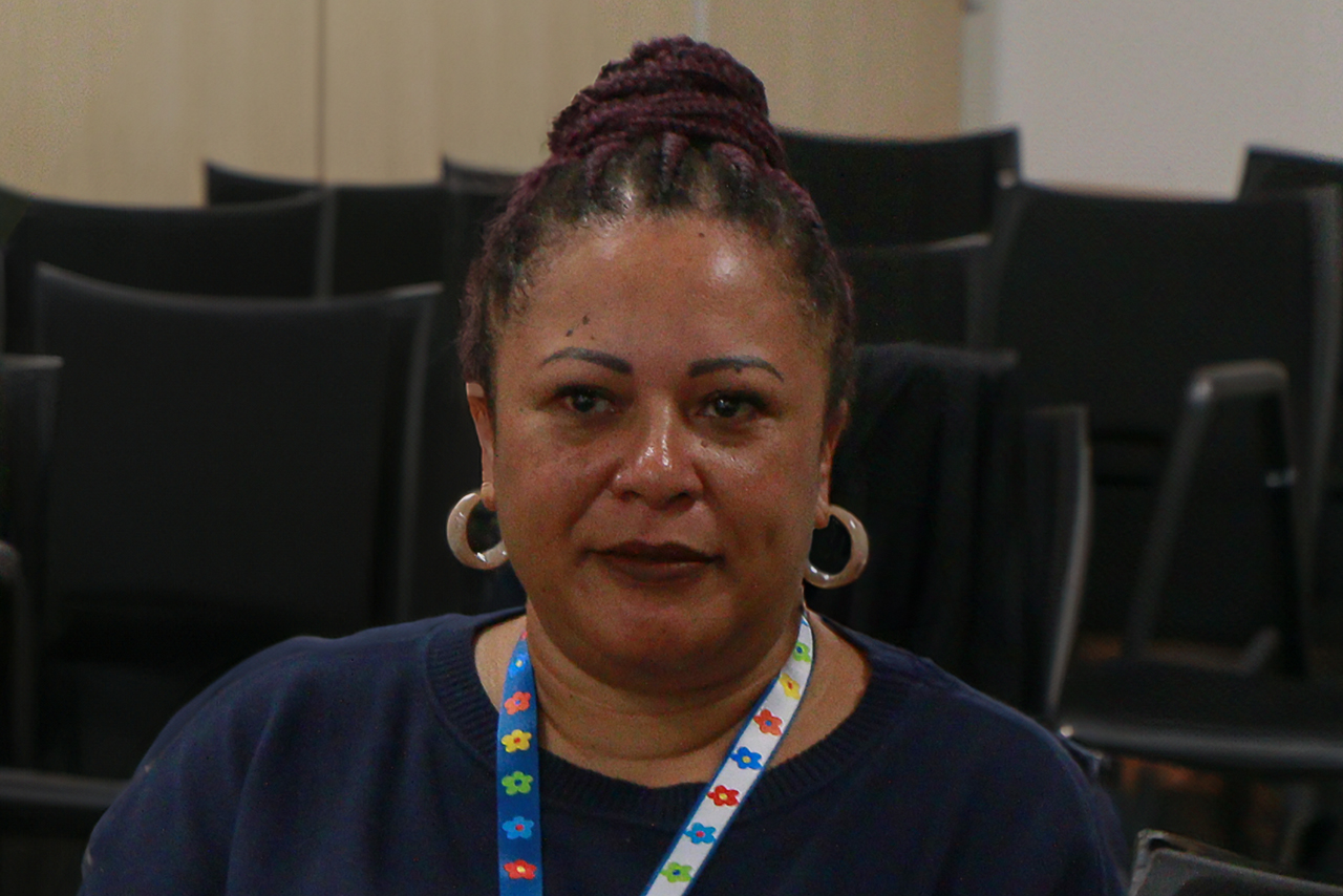 Foto da auditora fiscal de controle externo Walkiria Machado Rodrigues Maciel, uma mulher negra. Seus cabelos estão presos, com tranças e coque. 