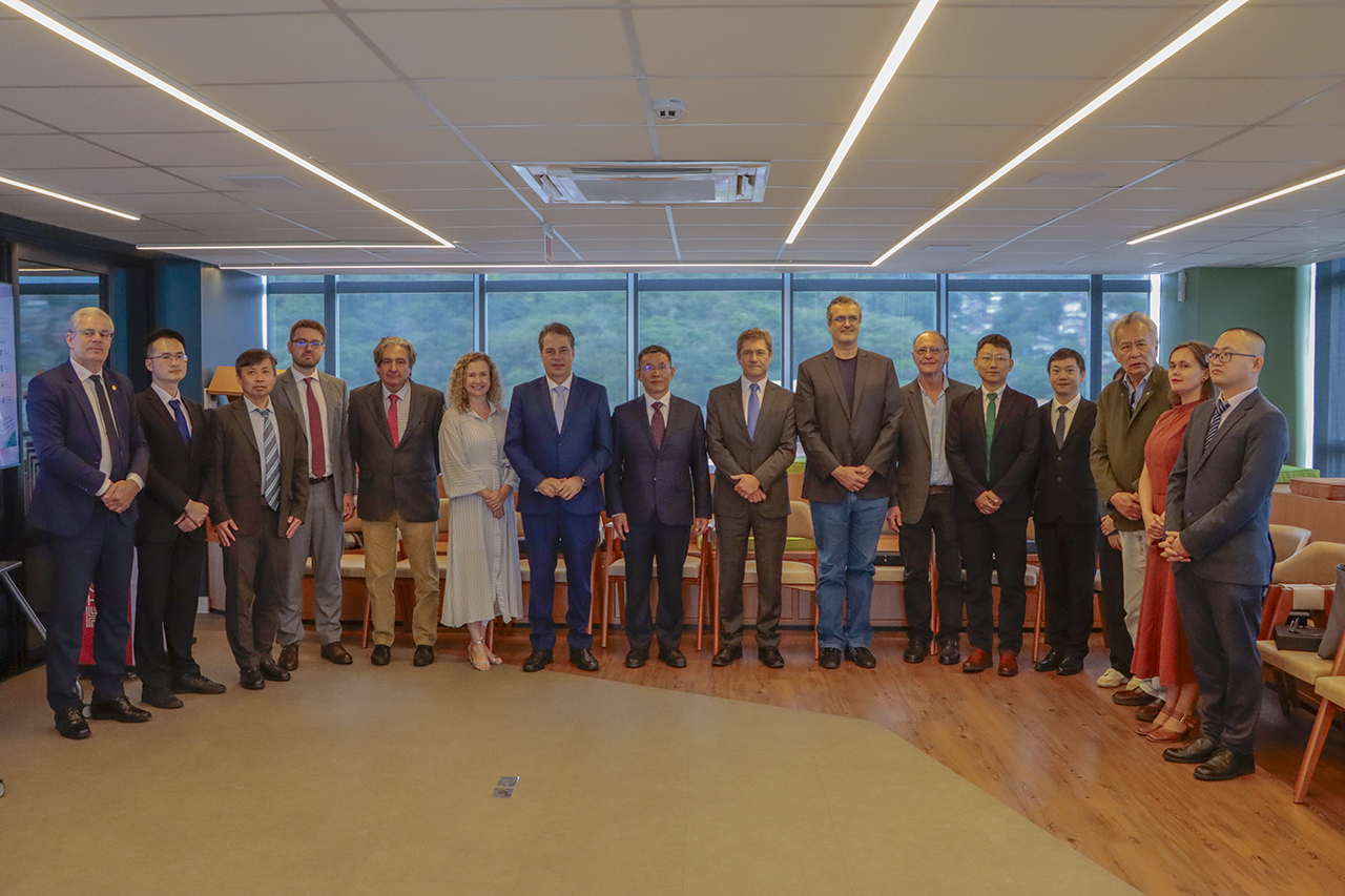 Banner horizontal com foto de visita institucional de uma comitiva chinesa ao TCE/SC. Na imagem, um grupo de 16 pessoas, formado por autoridades brasileiras e representantes de uma instituição chinesa, aparece posando lado a lado para uma foto oficial em uma sala de reuniões. Entre os presentes estão o vice-presidente José Nei Ascari, o conselheiro Aderson Flores e o conselheiro substituto Gerson Sicca, além dos integrantes da delegação chinesa. Os participantes vestem, em sua maioria, trajes sociais.