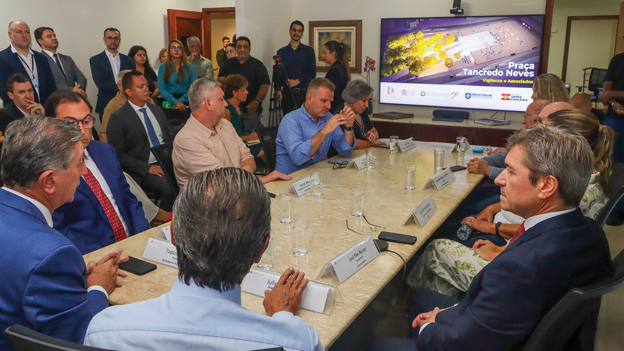 Foto de uma grande mesa de reunião com homens e mulheres sentados ao redor, entre eles o conselheiro Vice-presidente Nei AScari.