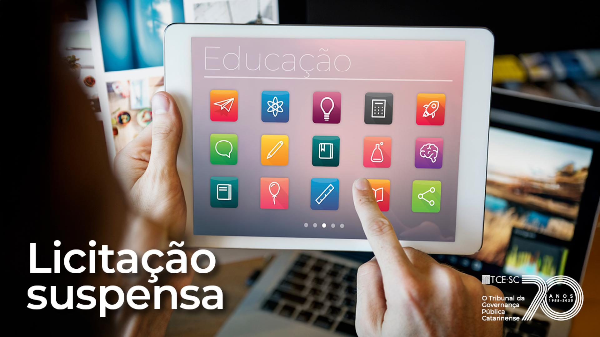 Banner horizontal com foto de uma pessoa segurando um tablet exibindo ícones coloridos relacionados à educação. No canto inferior esquerdo, há o texto “Licitação suspensa”, e no canto direito, logo do TCE/SC.  
