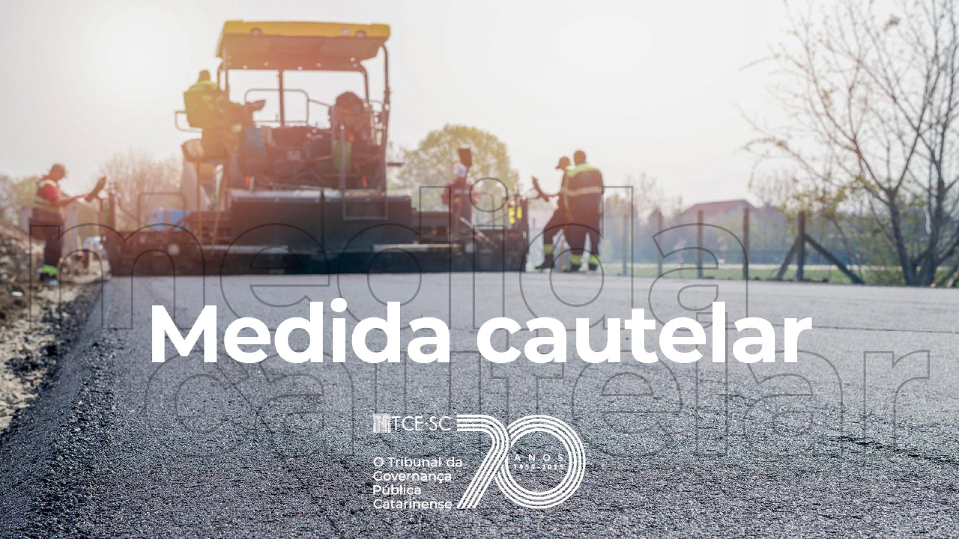 Banner horizontal com foto de uma obra de pavimentação. Em primeiro plano, superfície recém-asfaltada de uma via, enquanto ao fundo aparecem máquinas de construção e trabalhadores atuando no local. Sobre a imagem, em letras brancas, está o texto “Medida cautelar”, acompanhado da marca institucional do TCE/SC. 